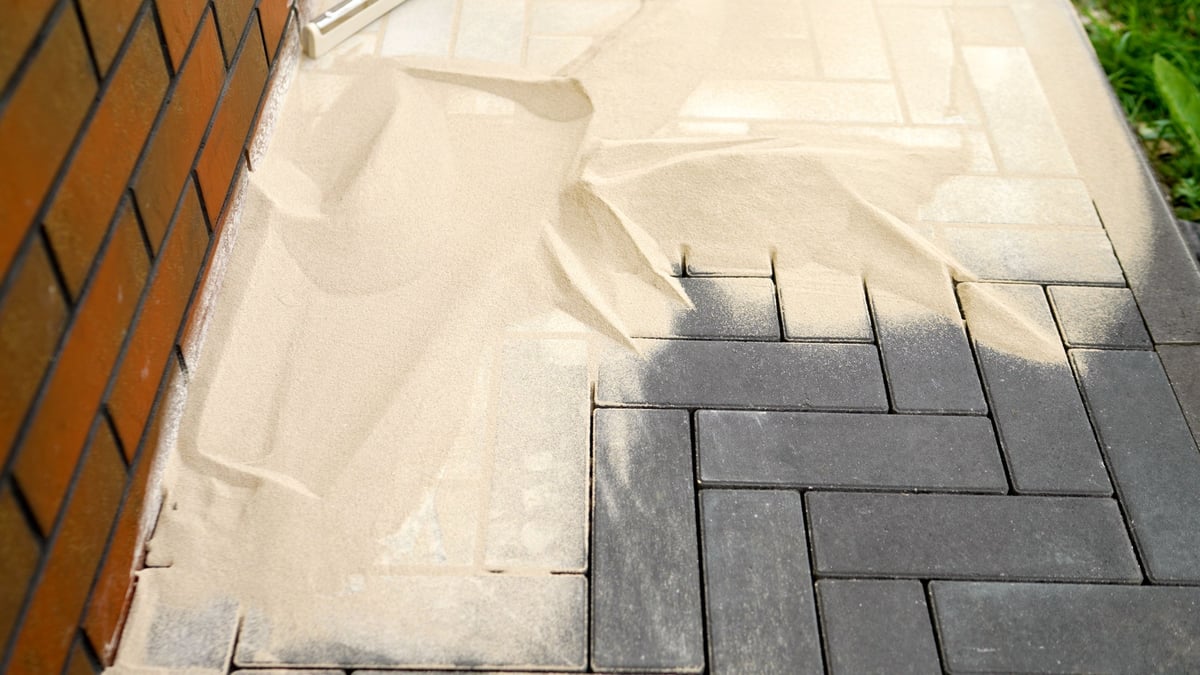 Filling the joints between paving stones with sand during the construction of a walkway or patio