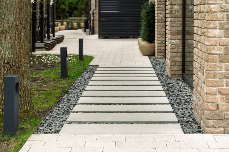 Modern walkway made of concrete slabs leads along landscaped area