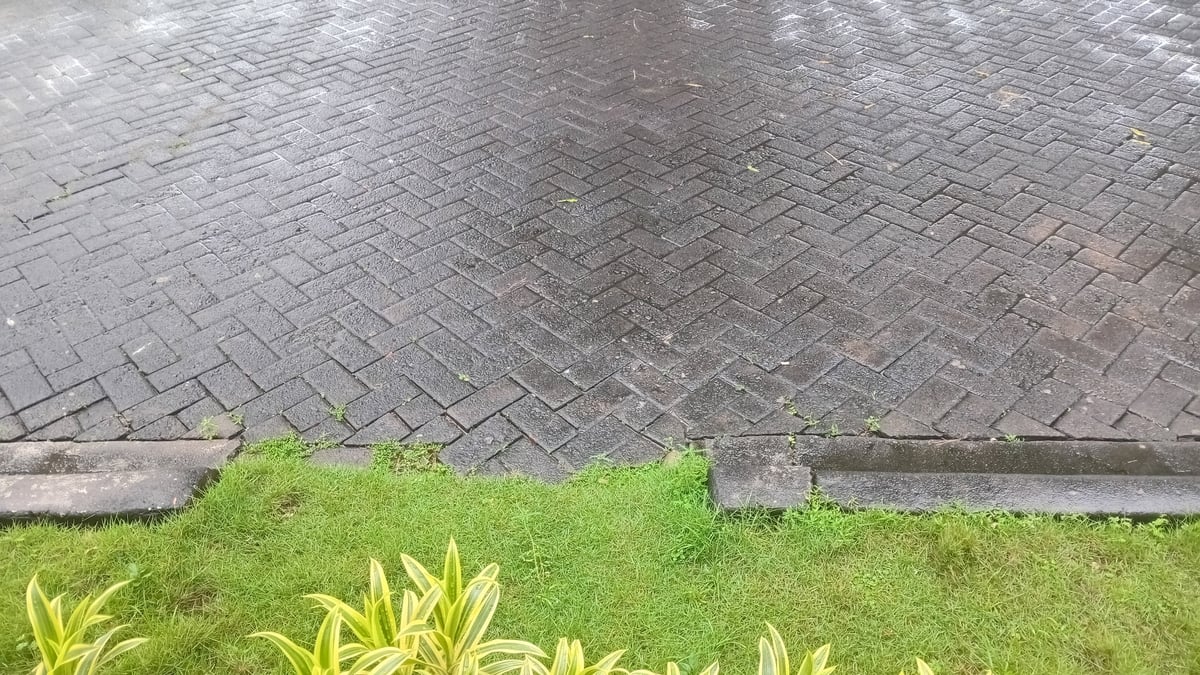 Professional paver sealing in action with wet herringbone brick pavement
